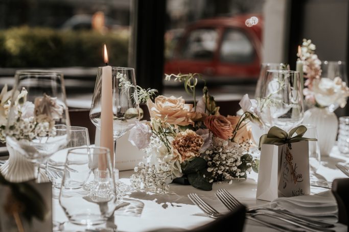 Elegant gedeckter Tisch mit Blumen, Kerzen und stilvollen Gläsern.