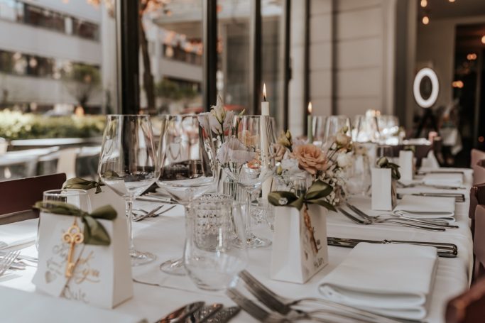 Elegant gedeckter Tisch mit Blumenarrangements und Kerzen in einem modernen Restaurant.