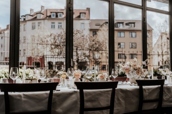 Festlich gedeckter Tisch mit Blumen, Blick auf eine Straße und Gebäude außerhalb.